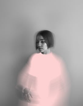 Creative portrait of a woman with motion blur on grey background, evoking emotion.