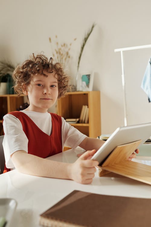 Free Child Sitting at Desk with Tablet Stock Photo