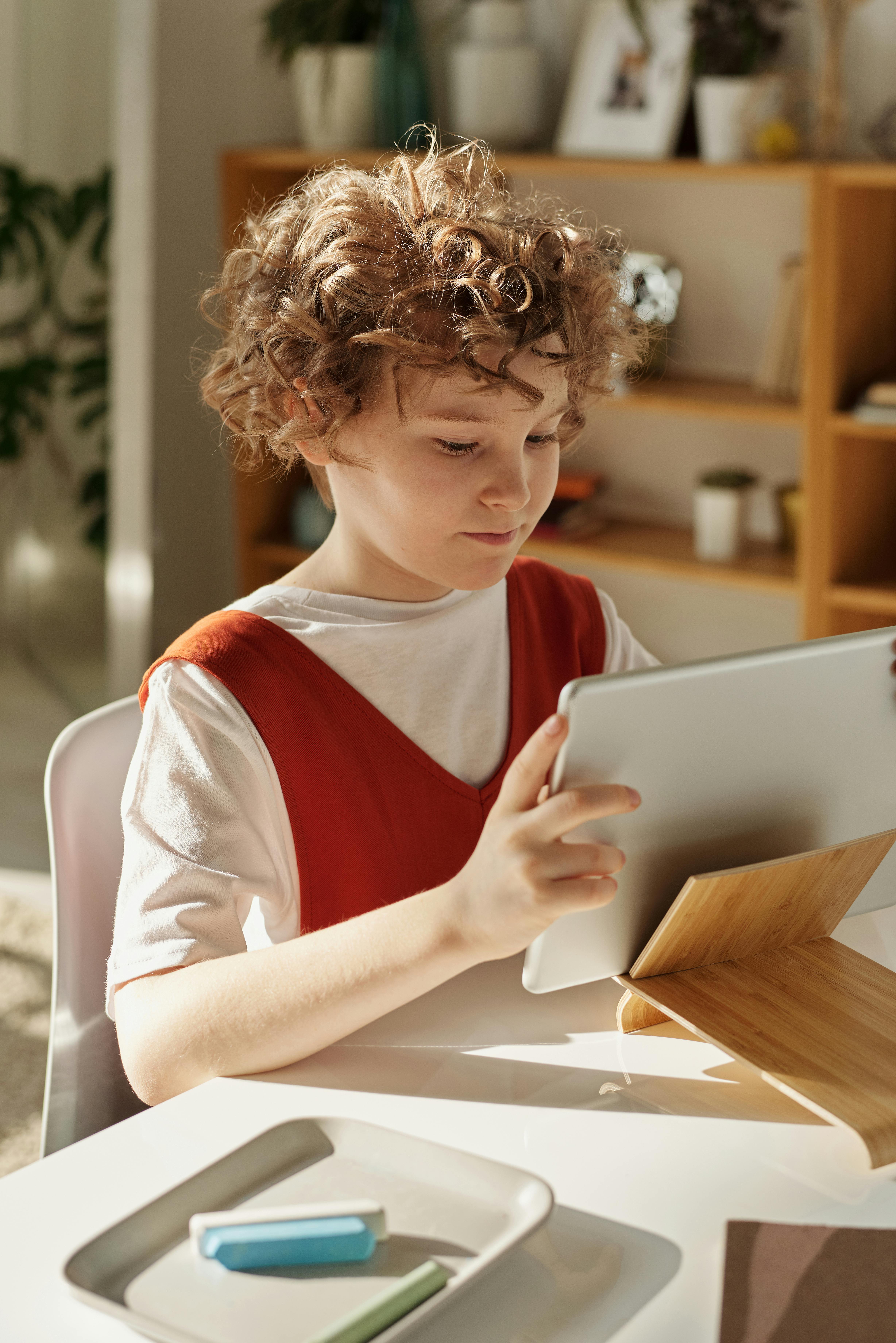 girl in white and red shirt using silver tablet