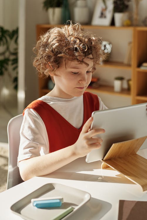 Girl in White and Red Shirt Using Silver Tablet