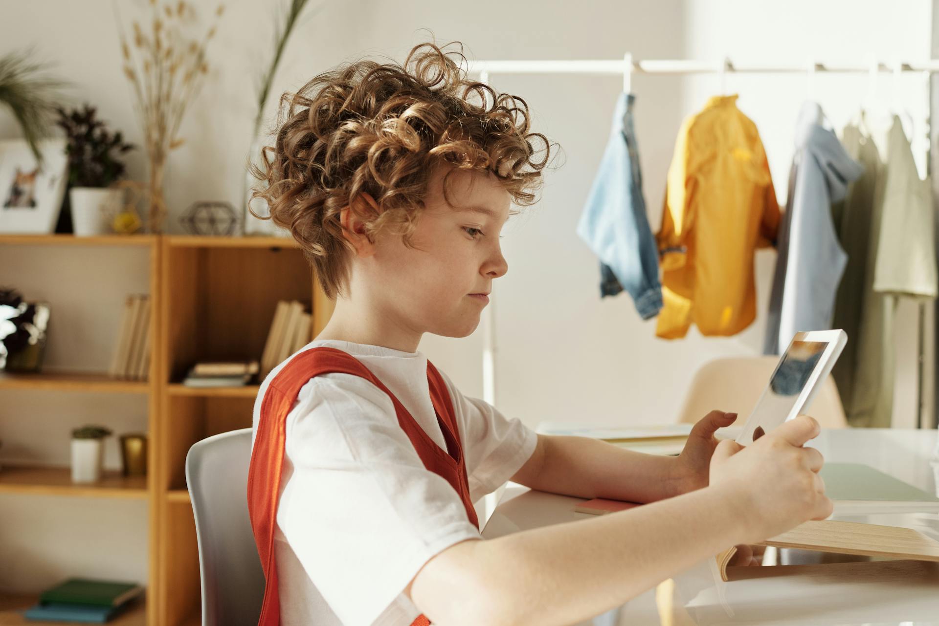 Child focused on using a tablet indoors, engaging in distance learning activities.