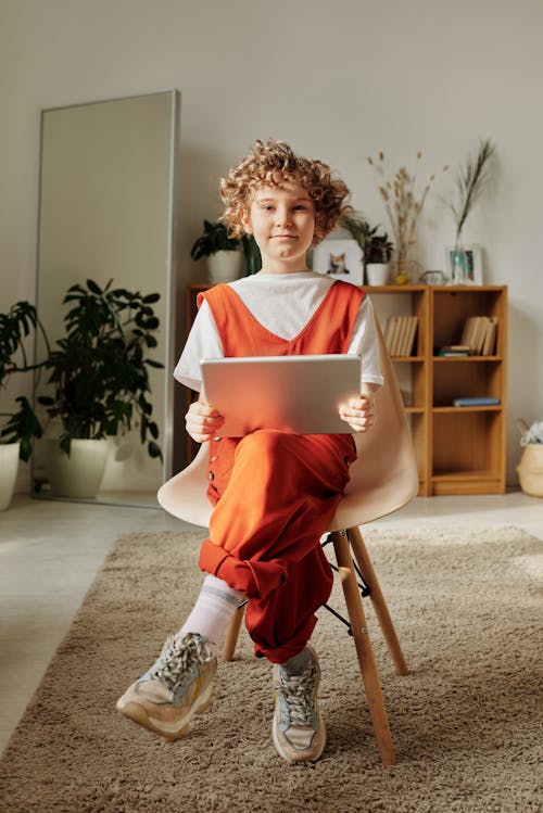 Free Photo of Child Sitting on Chair While Using Tablet Stock Photo