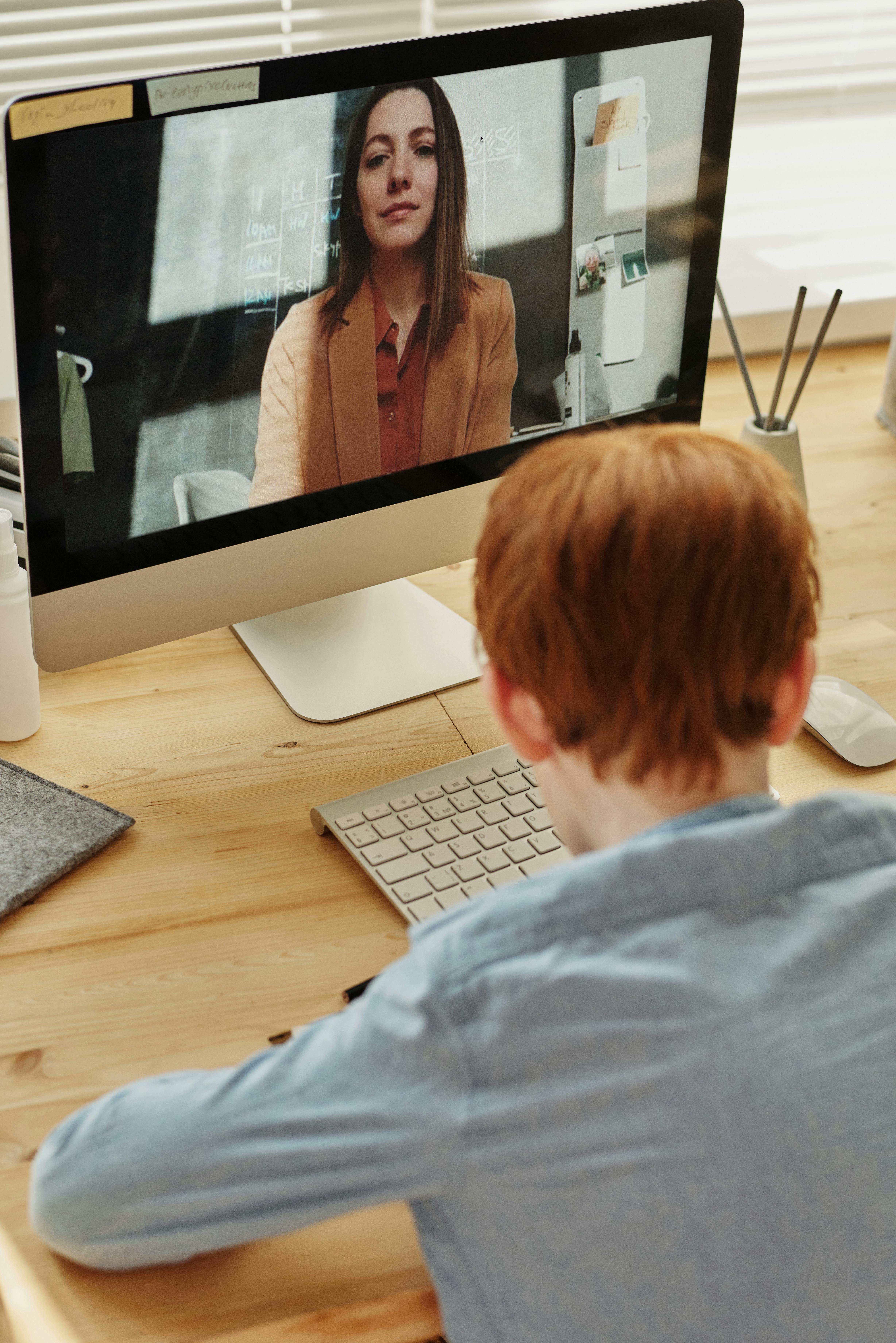 photo of boy in blue dress shirt while video calling with a woman through imac