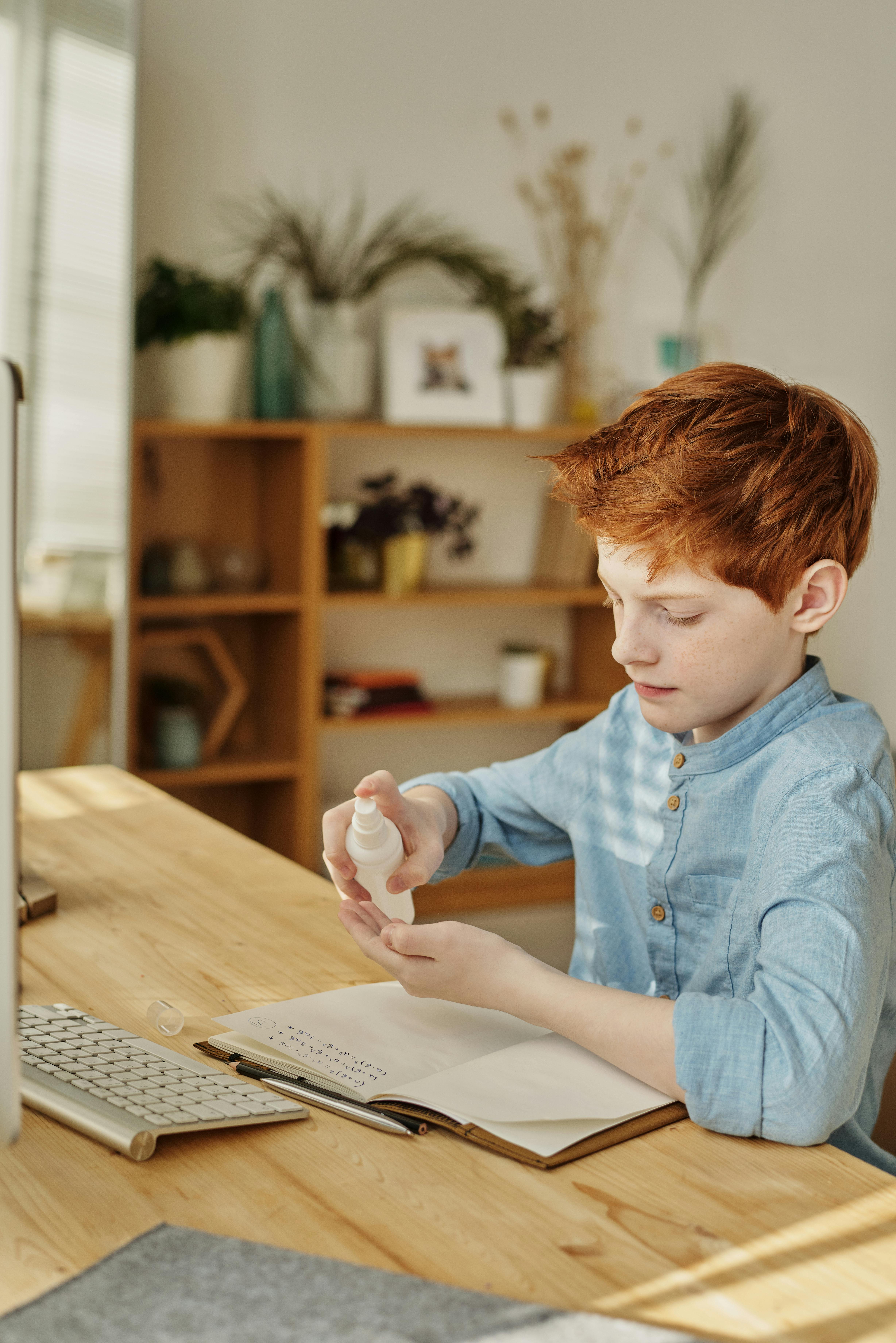 boy in blue dress shirt spraying hand sanitizer