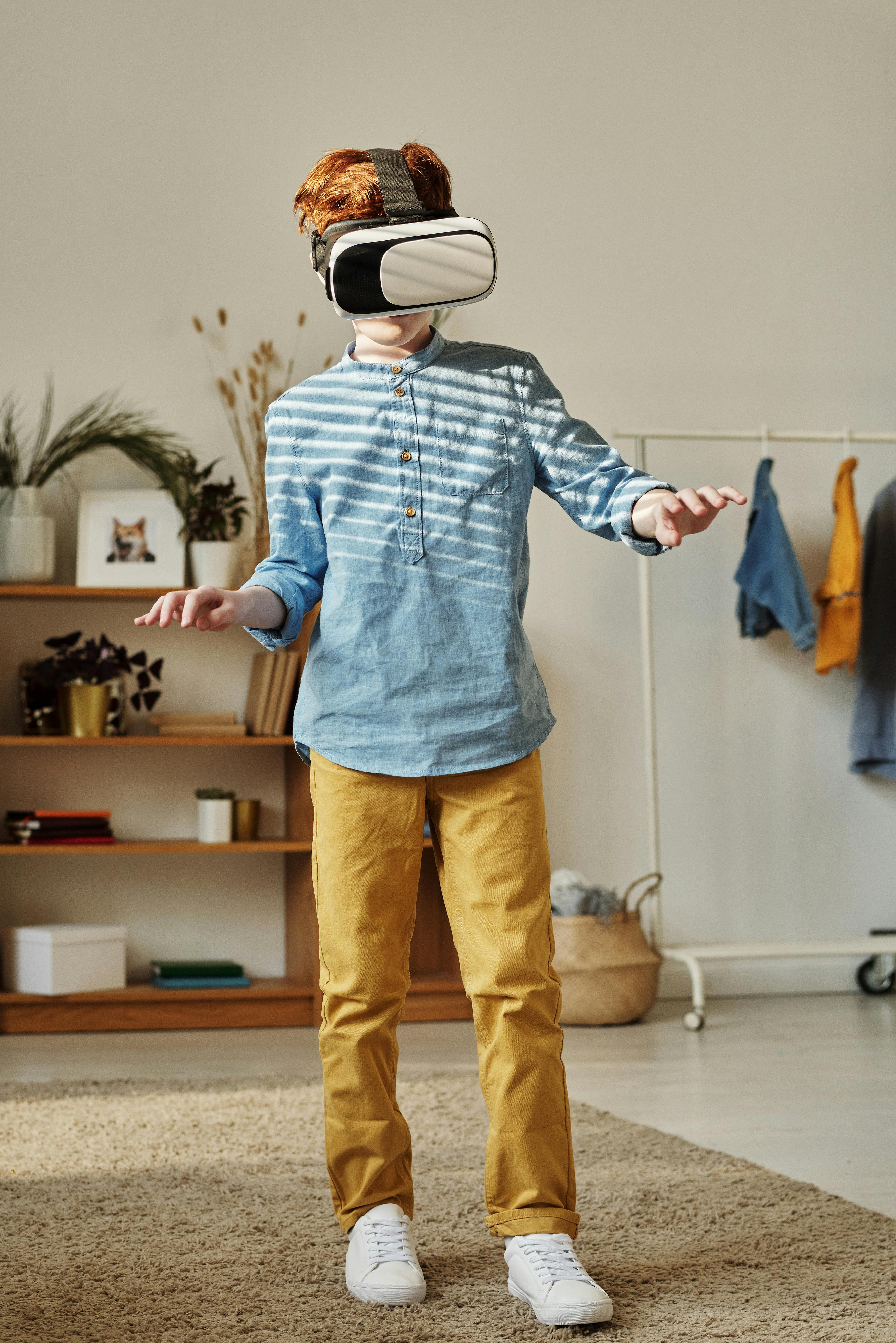 boy in blue dress shirt and brown pants while using vr headset