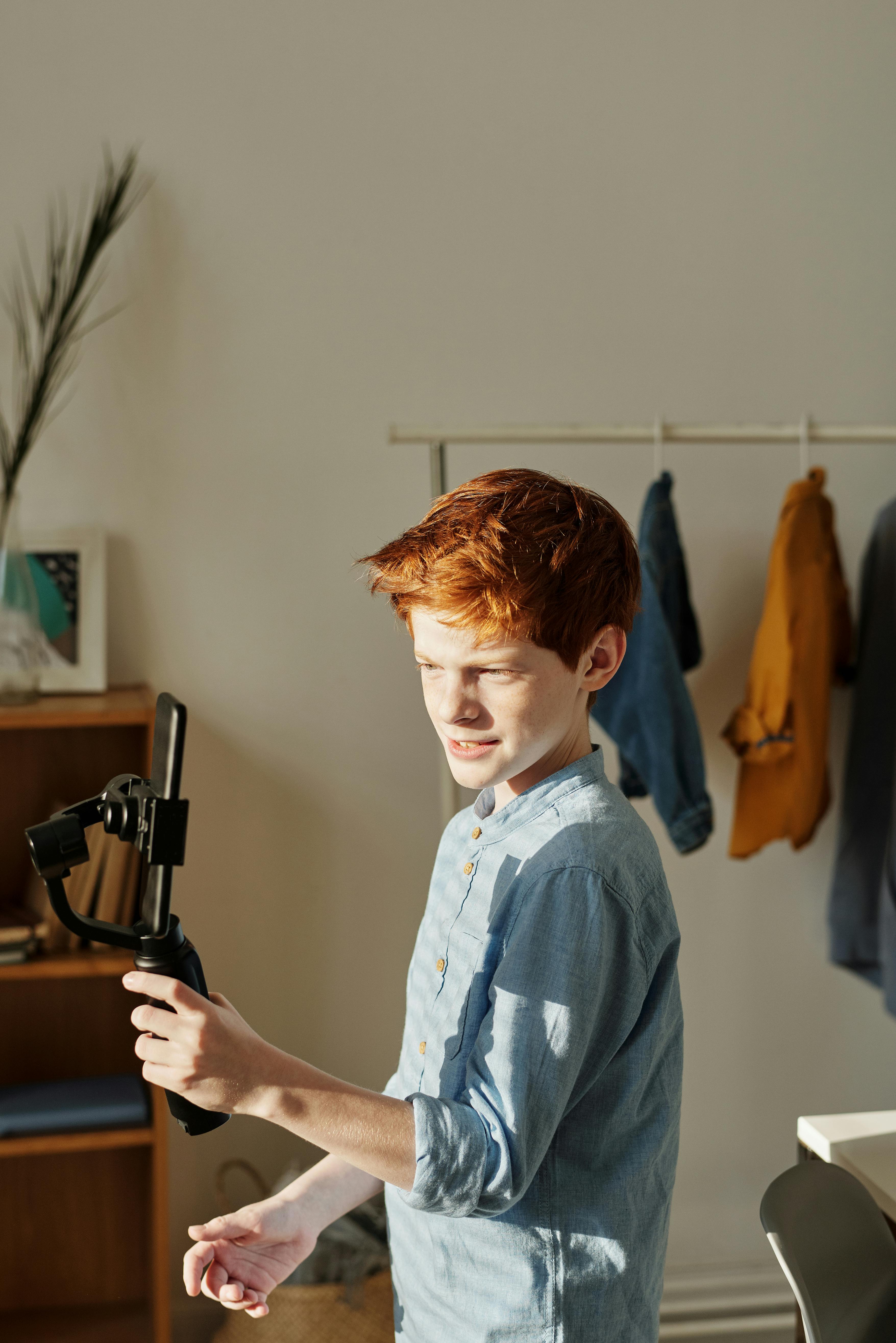 man in blue button up shirt holding black selfie stick