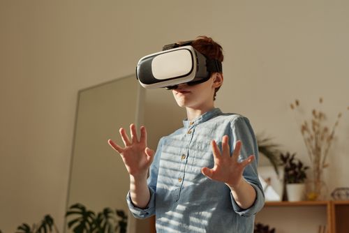 Free Young boy in blue shirt using VR headset indoors for gaming fun. Stock Photo