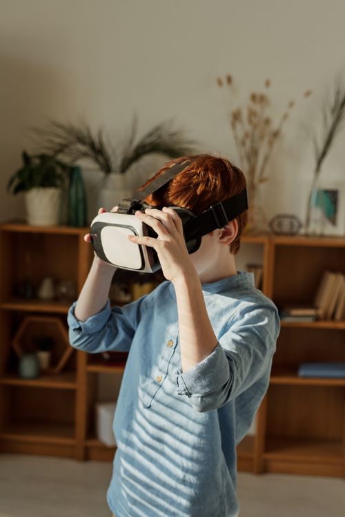 Free Young boy with red hair using VR headset in cozy indoor setting Stock Photo