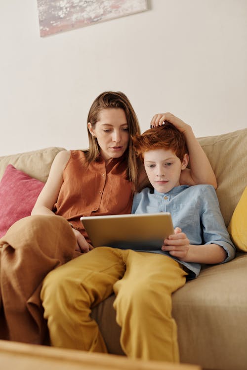 タブレットコンピュータを通して見ている女性と少年の写真