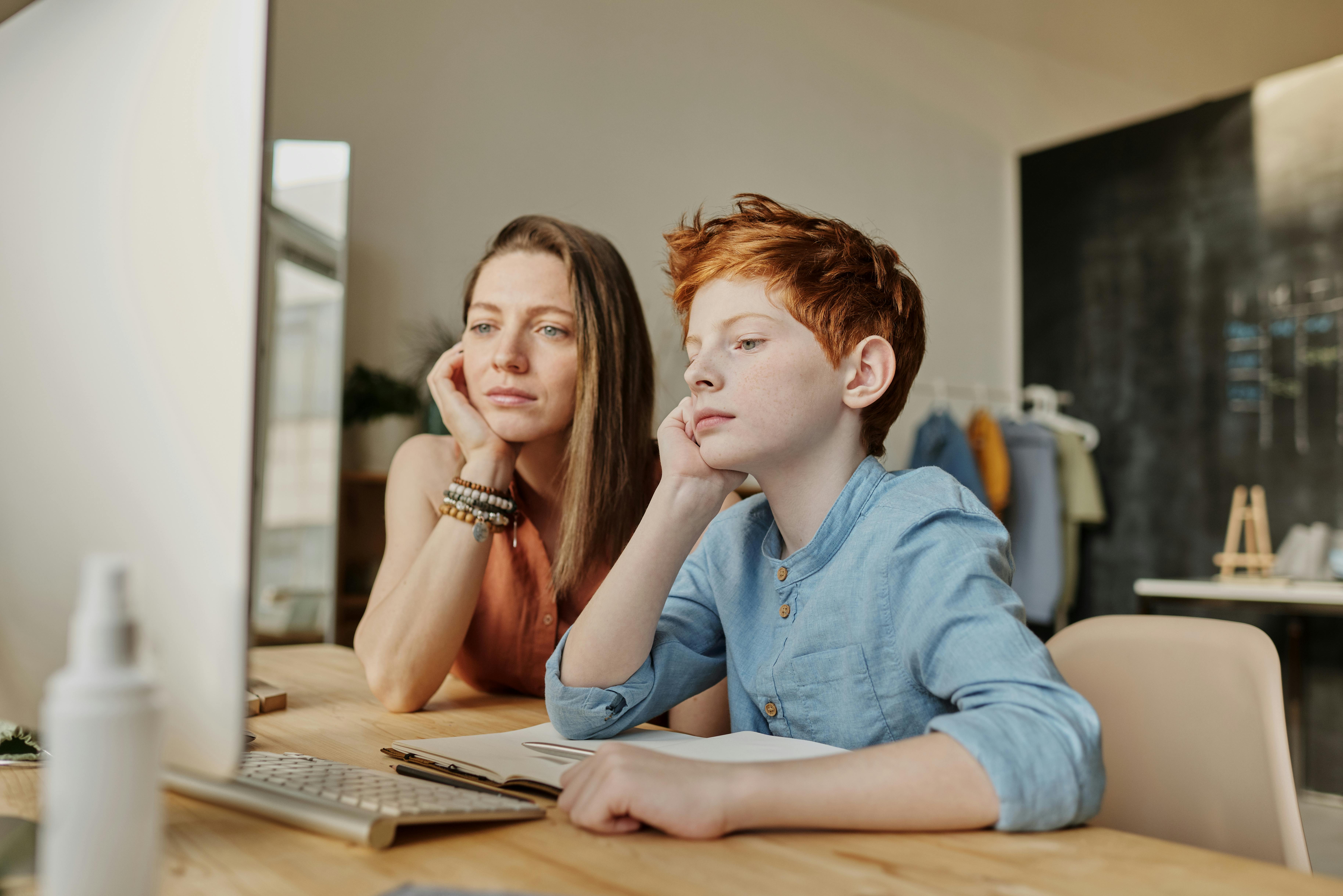 photo of woman and boy leaning on wooden table