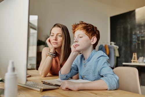 Photo of Woman and Boy Leaning on Wooden Table