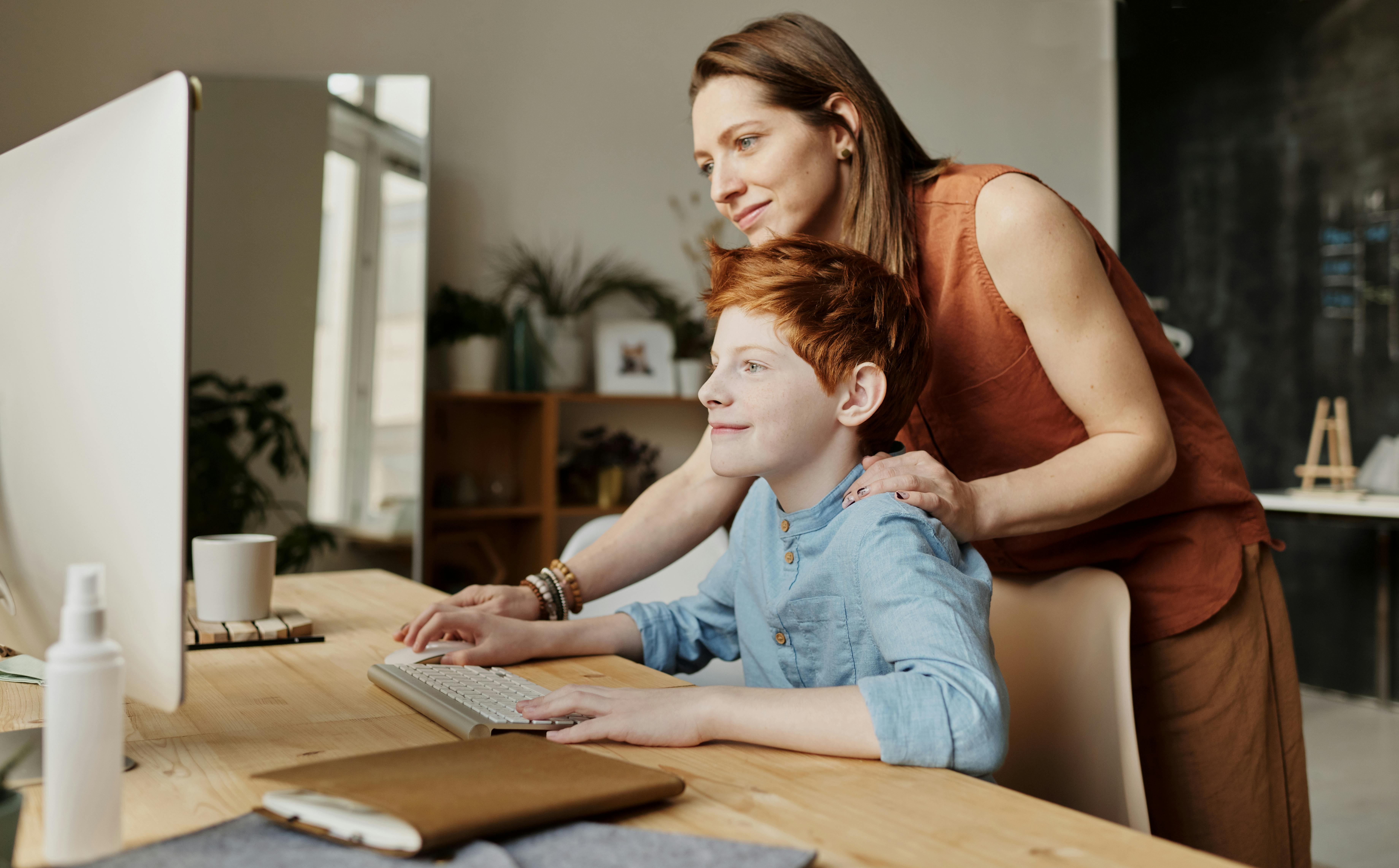 photo of woman teaching his son while smiling