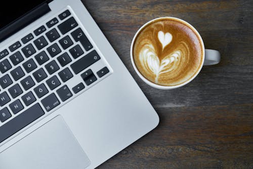 Free Teacup of Latte Beside Macbook Pro Stock Photo