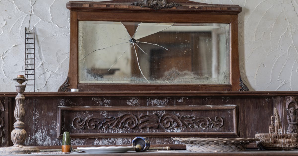An antique wooden sideboard with a cracked mirror in a rustic setting, showcasing vintage decor.