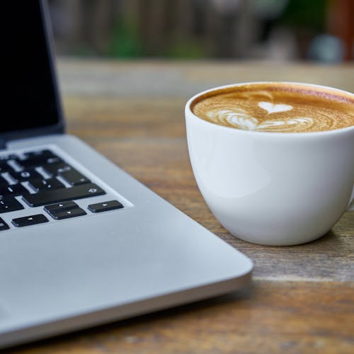 Teacup of Latte Beside Macbook Pro