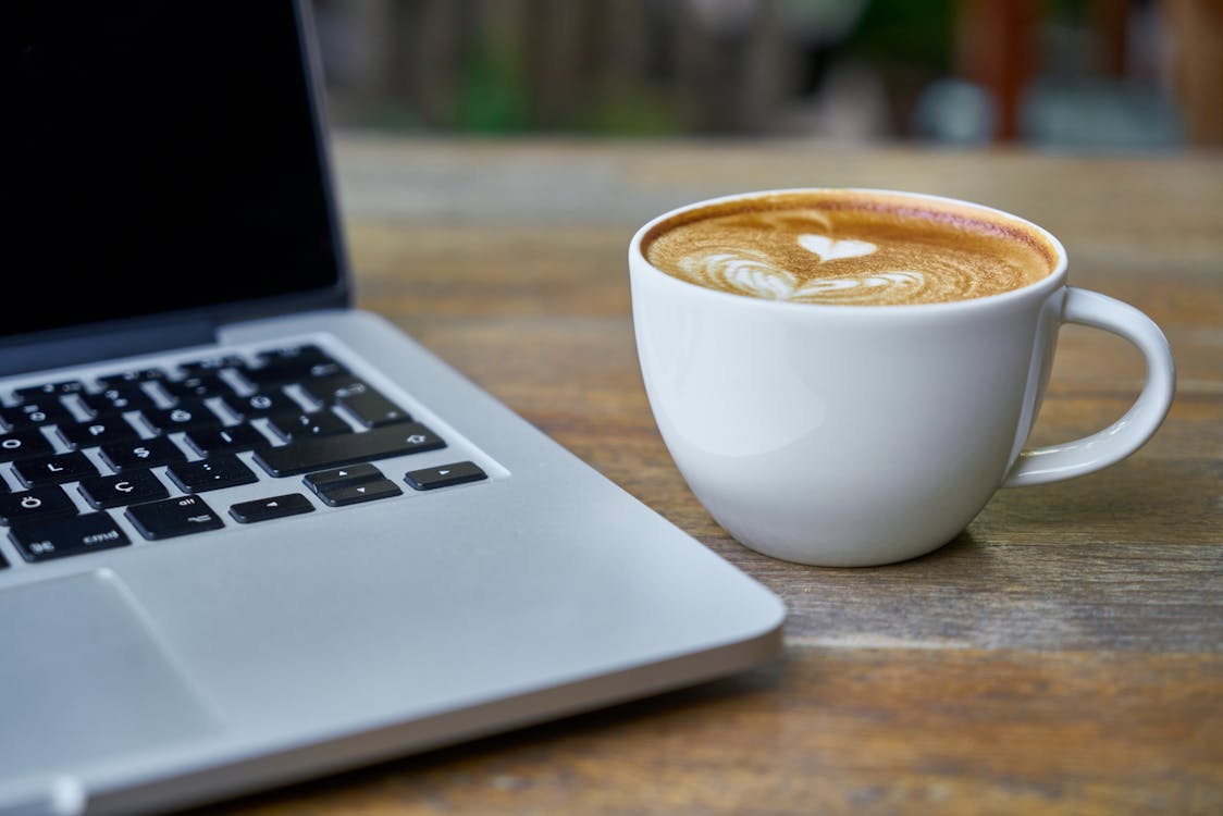 Free Teacup of Latte Beside Macbook Pro Stock Photo