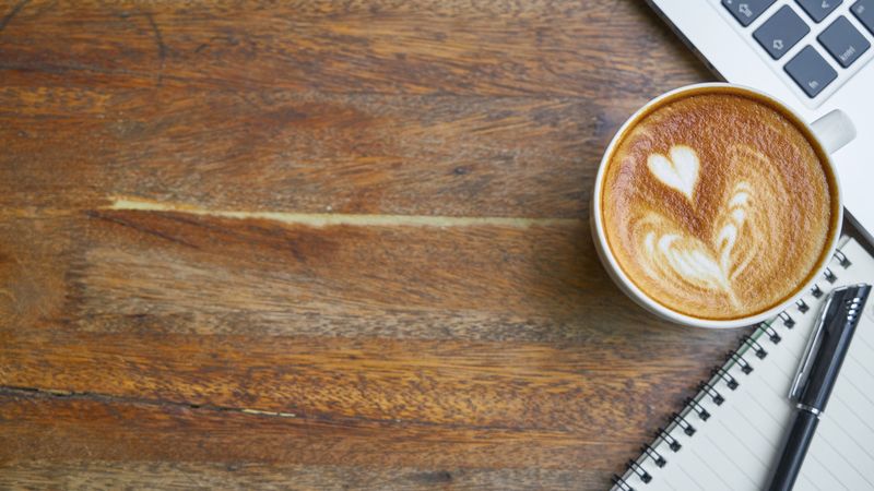 A warm cup of coffee on a wooden table, representing the popularity of CBD and caffeine functional beverages.