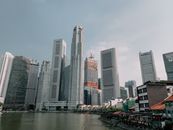 新加坡河畔，现代摩天大楼高耸入云，在晴朗的天空下勾勒出壮丽的天际线