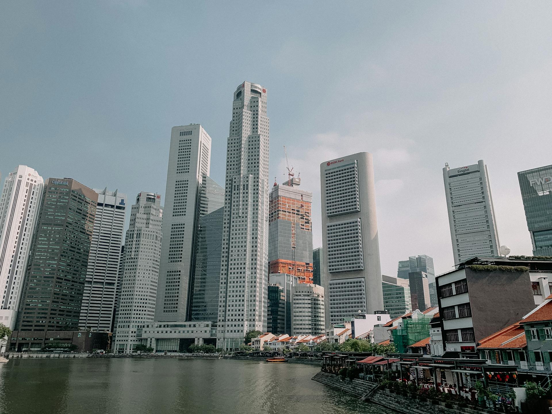 Skyline view of modern skyscrapers towering above the Singapore River with clear skies.