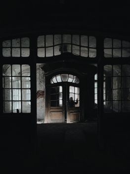 废弃建筑光线昏暗，门口怪异，玻璃窗破碎