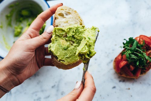 Free A Person Holding a Bread with Avocado Spread Stock Photo