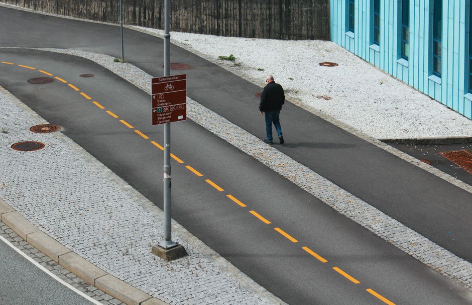 A man walks down an urban street in Bergen, Norway. Perfect for city life themes.