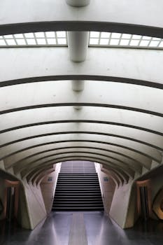 现代地铁隧道内部，弯曲的混凝土设计和上升的楼梯映入眼帘