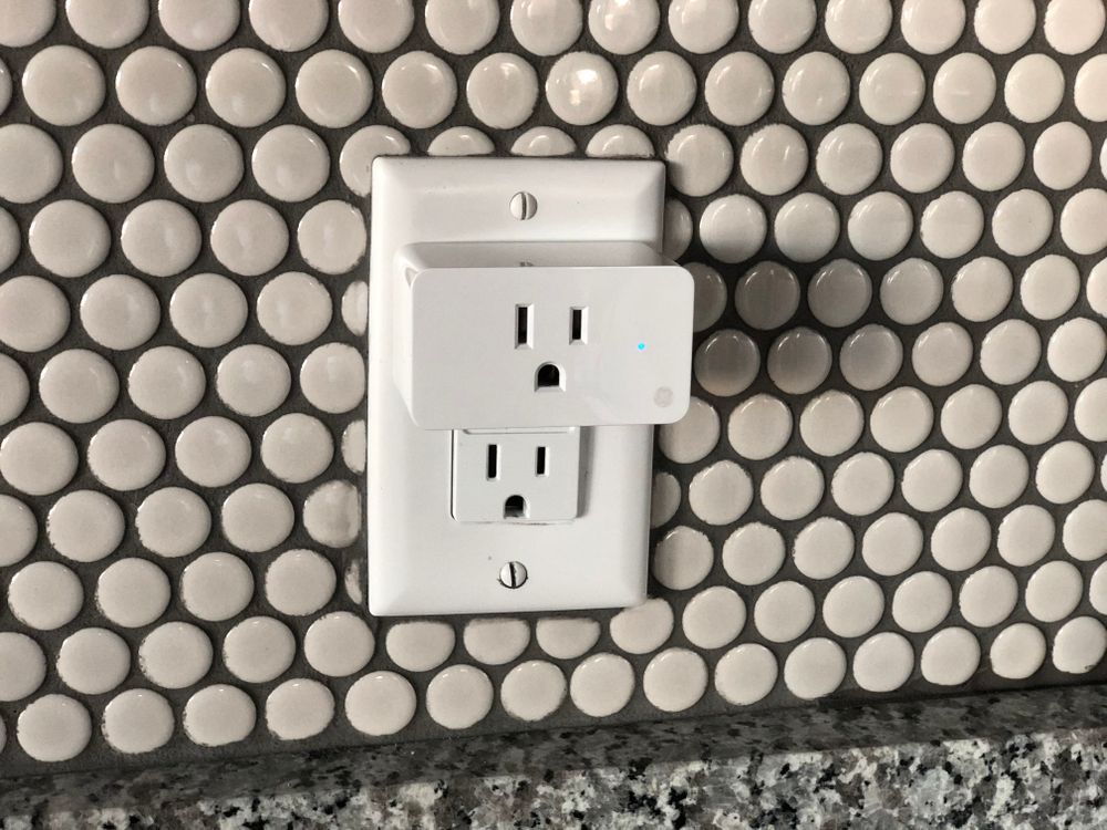 Close-up of a smart plug installed on a wall outlet in a rental apartment
