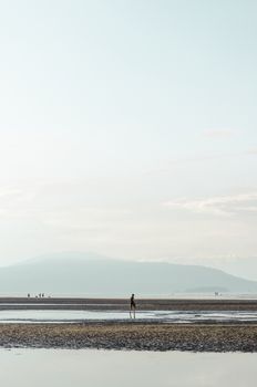 退潮时，一个人走在安静的海滩上，场景平静而安宁