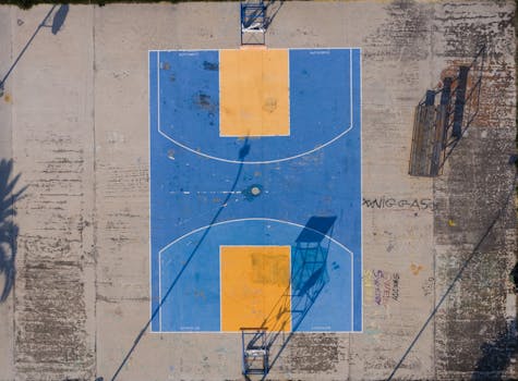 Top-down drone view of a colorful basketball court in Lanciano, Italy, with vibrant blue and yellow design.