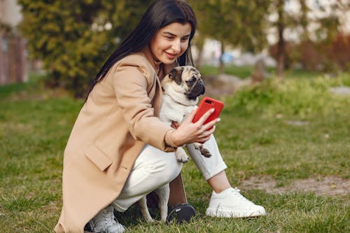 Woman in Brown Coat Holding Brown Pug