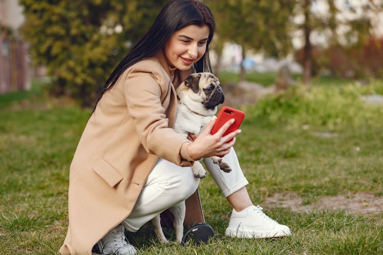 Woman In Brown Coat Holding Brown Pug