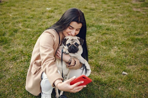 Free Woman in Brown Coat Holding Her Dog While Taking Selfie Stock Photo