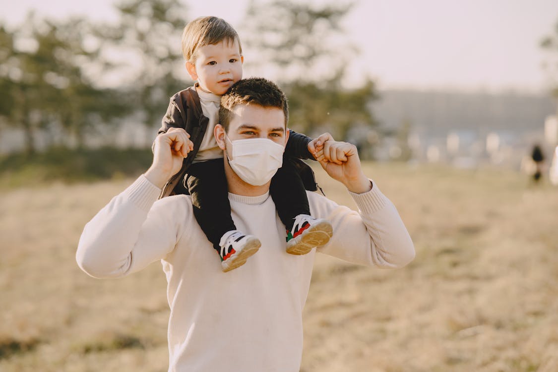Man in White Long Sleeve Shirt Carrying Baby on His Back