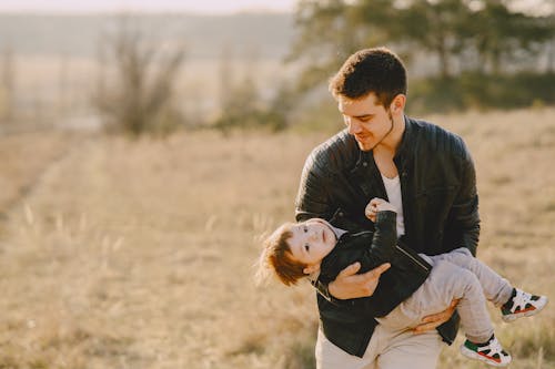 Free Man in Black Leather Jacket Carrying His Child Stock Photo