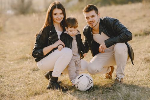 Free A family enjoys a warm day bonding and playing soccer outdoors in the park. Stock Photo