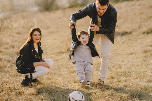 Free Family enjoying playful soccer game outdoors, capturing joyful moments. Stock Photo