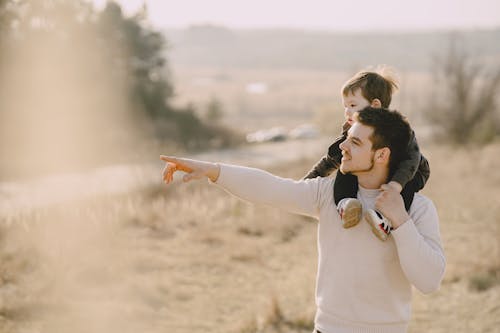 Free Photo of Man Carrying His Child While Pointing to His Right Stock Photo