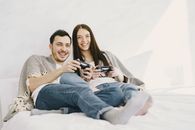 Happy couple playing game console while lying on bed