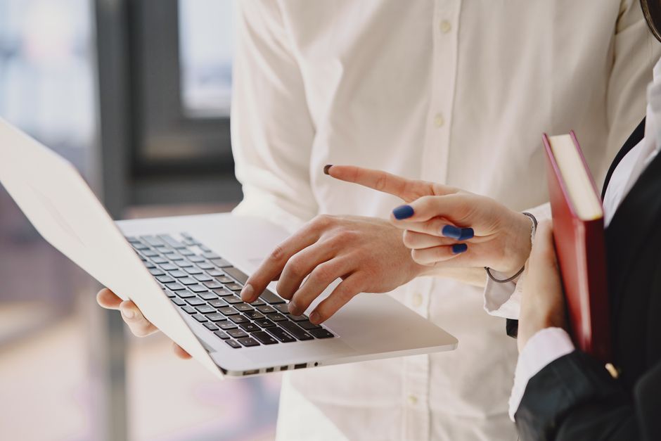 Profesionales de negocios discutiendo un proyecto usando una laptop en interiores.