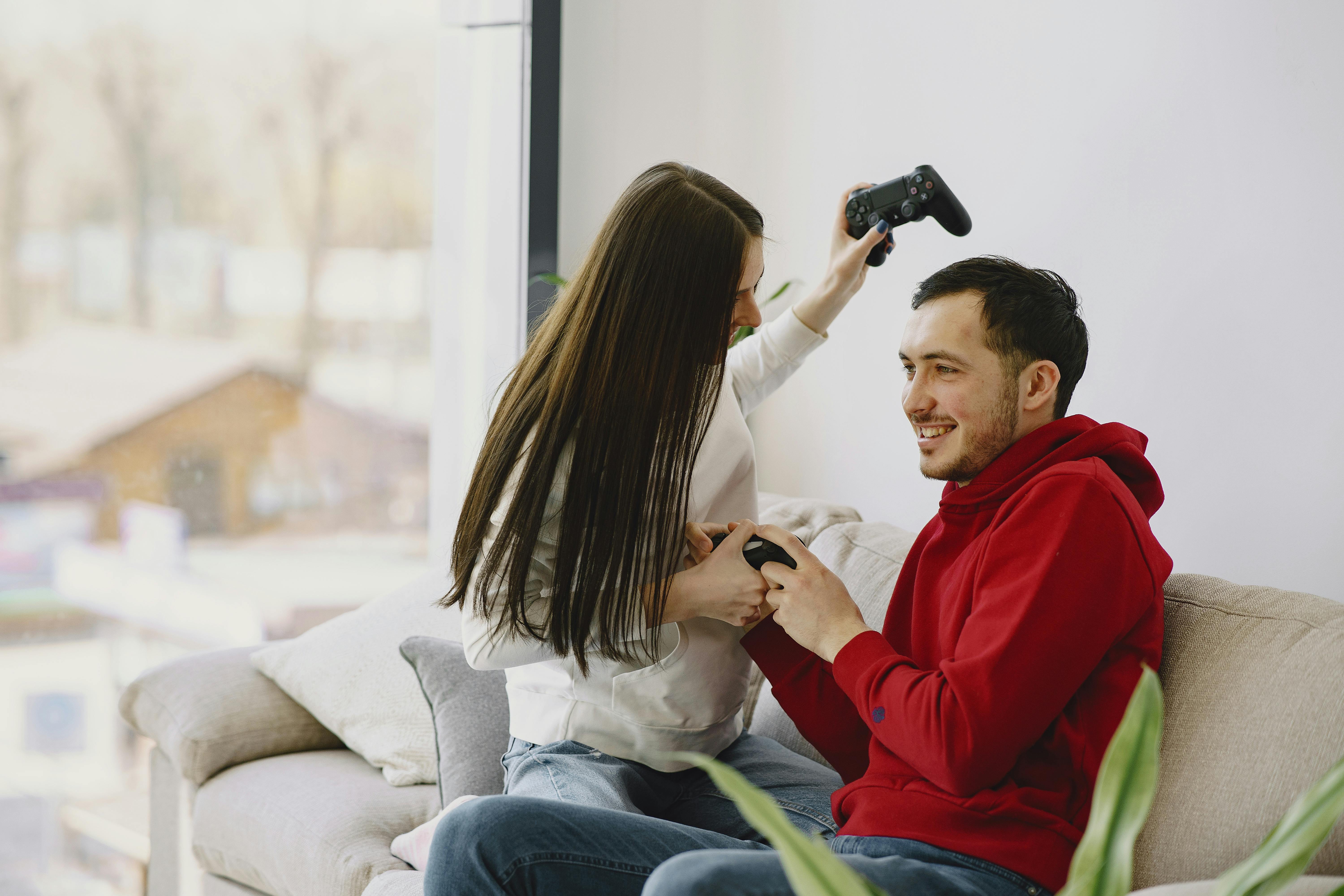 Happy Couple Sitting on the Sofa Playing Video Games, Using Controllers.  Competitive Girlfriend and Boyfriend in Love have Fun Playing in Online  Video Games at Home Together. Close-up Focus on Hands Stock