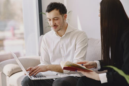 Smiling male coworker with laptop and female colleague with book