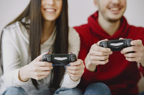 Crop smiling friends in casual clothes with gamepads