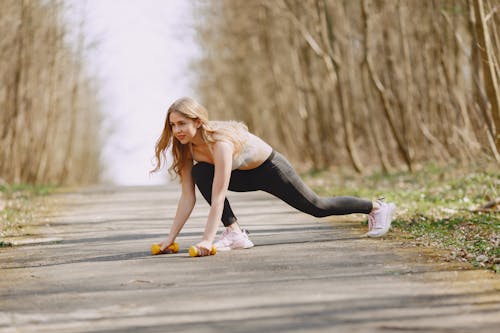 Photo of Woman Exercising With Dumbbells on a Pavement