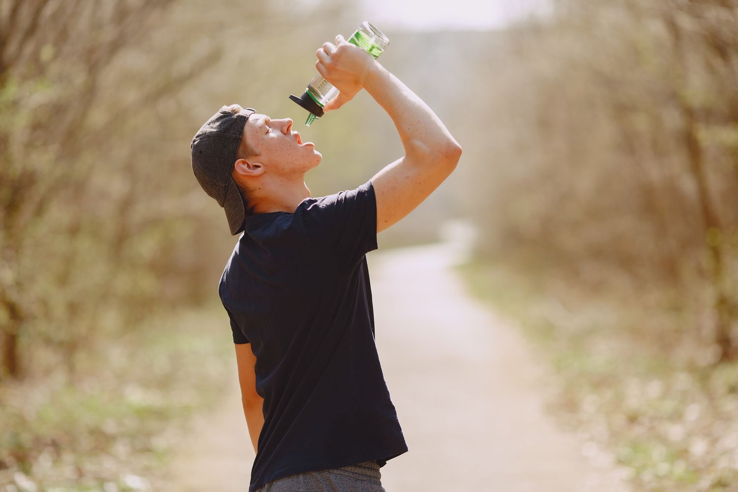 Runner drinking water during a training break in a park