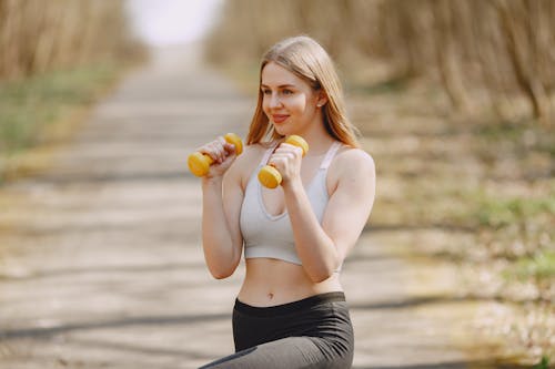 Woman in White Sports Bra and Black Leggings Holding Yellow Dumbbells