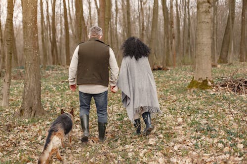 Man and Woman Walking on Forest With Their Dog