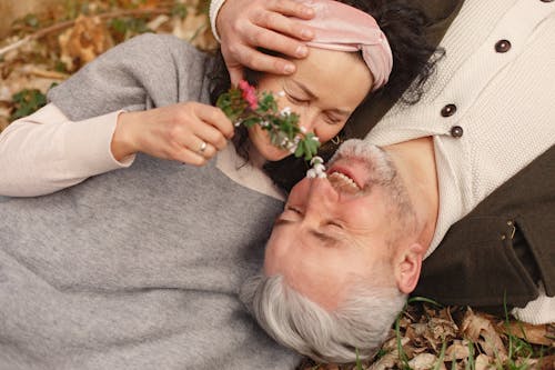 Счастливая пара старших в любви с букетом свежих цветов на природе