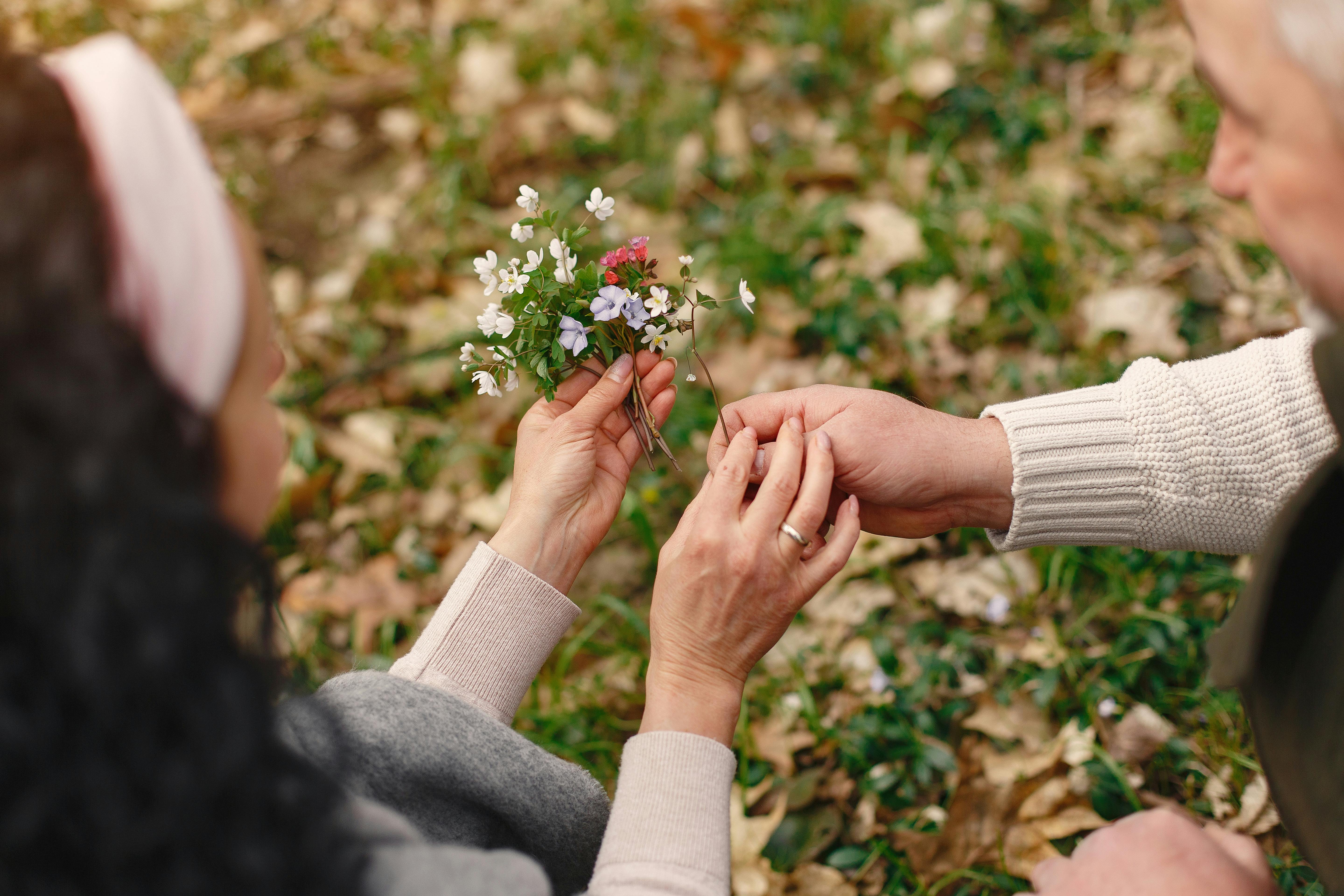 crop senior couple holding flowers in park