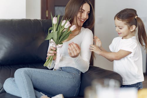 Free Happy mother and daughter giving flowers to mother at home Stock Photo